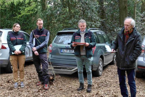 Team der Landesforsten vor geparkten Autos auf Waldparkplatz